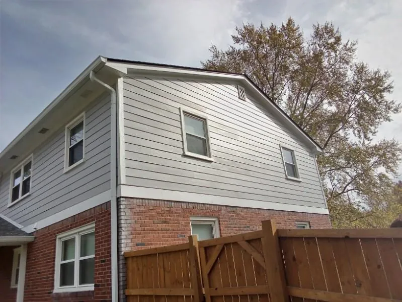 Two-story home with new gray lap siding on the upper floor above original brick
